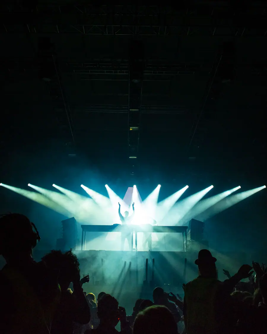 Crowd facing a stage with beams of light