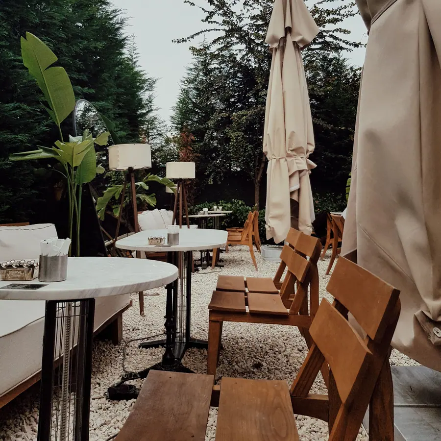 Outdoor café terrace with wooden chairs, round tables and umbrellas